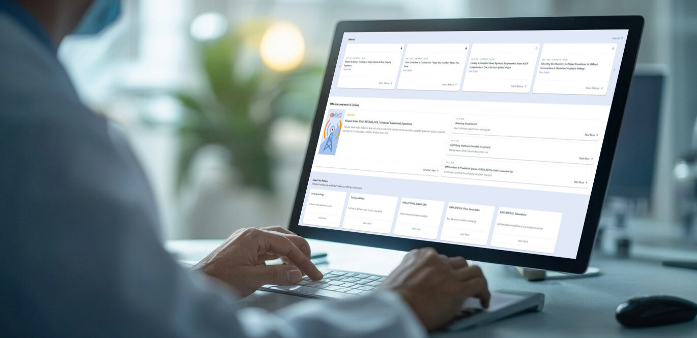 Person using a desktop monitor displaying a dashboard with multiple cards and charts on a light desk in an office.
